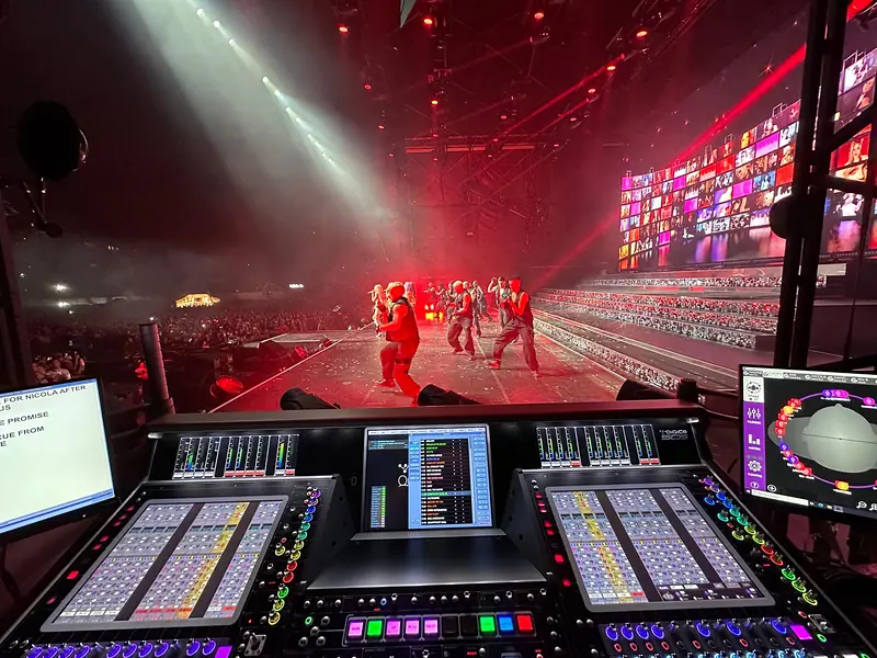 DiGiCo Quantum 5 console with dancers and a video wall on stage under red lighting