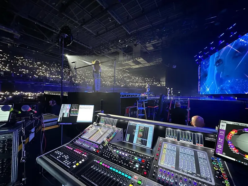 DiGiCo Quantum 5 console in the foreground with a singer on stage and a crowd lit by phone lights